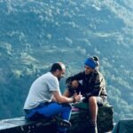 Dos aventureros descansando en un tramo de la escalada en el fondo la ladera de una montaña del Himalaya