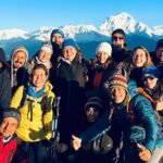 Parada de un grupo de aventureros al conseguir llegar a su objetivo y al fondo de la imagen se observa parte de las cimas del Himalaya nevadas