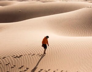 Entre las dunas del desierto del Sahara se observa una persona como encontrándose a si mismo.